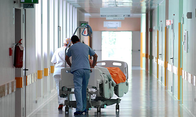 Migrazione sanitaria, Sud, corridoio di un ospedale con operatore che trasporta letto