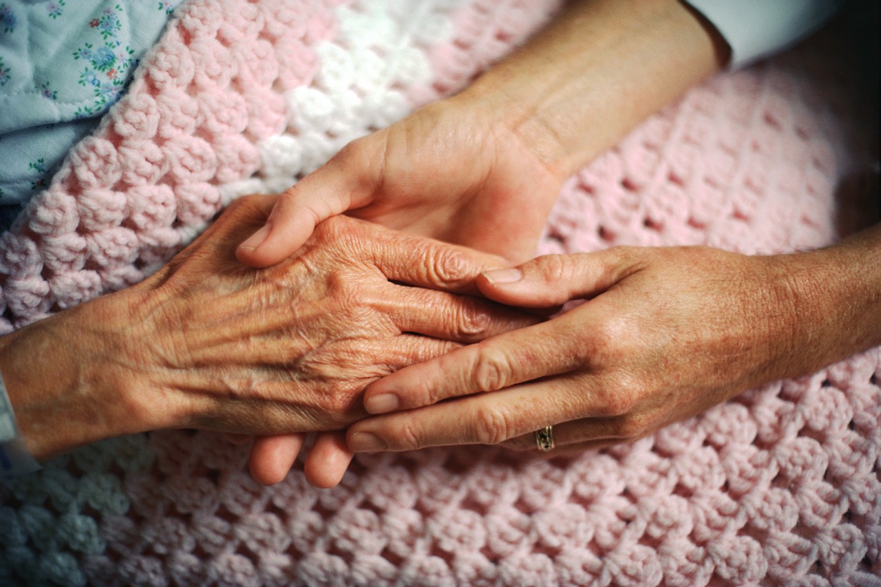 Cure palliative, un medico stringe le mani di una donna