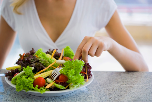 Una donna mangia ortaggi e verdure.