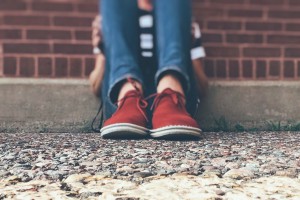 bullismo: i piedi di un adolescente seduto sul marciapiede