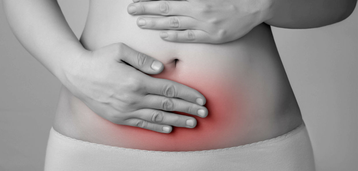 Crohn, pancia di donna in bianco e nero con mani sul ventre arrossato