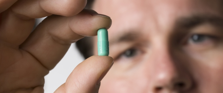 L’antibiotici: un uomo con una pillola tra le dita della mano