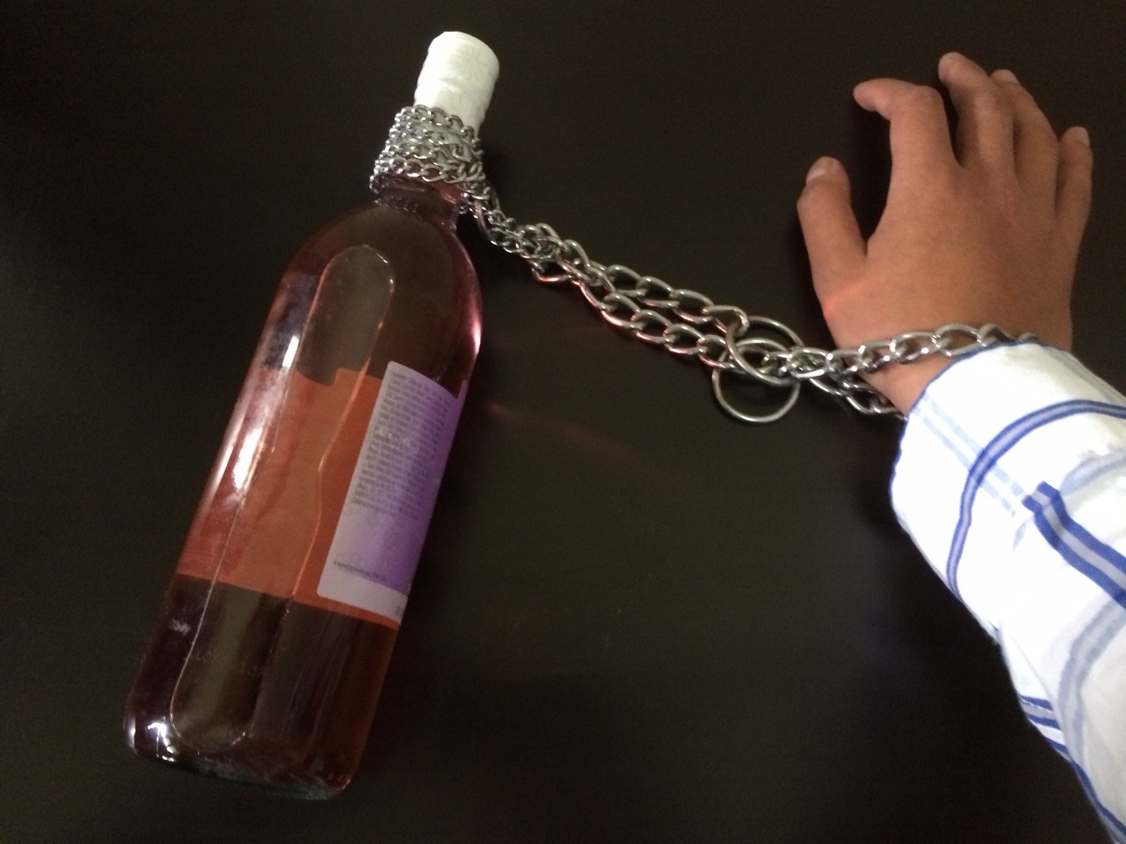 Alcol, bottiglia di vino vuota legata con una catena al polso di una persona