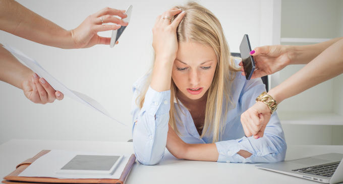 Giovani ipertesi, una donna seduta alla scrivania e in preda allo stress da lavoro