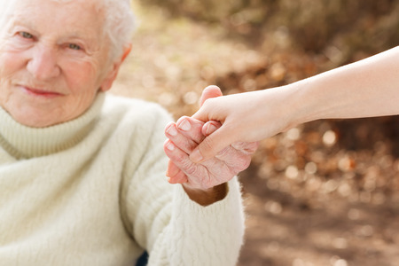 31072401 – elderly woman holding hands with young woman outside