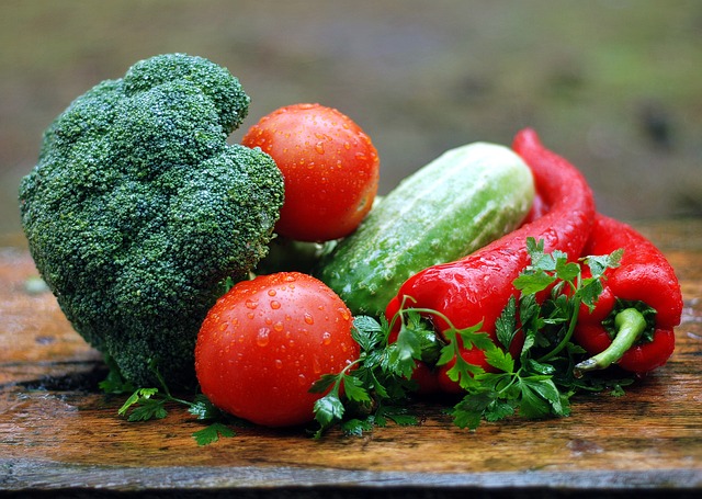 alimentazione sana: in primo piano un broccolo, due pomodori e un peperone