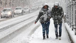 Una donna e un uomo camminano sotto la neve al freddo indossando dei cappotti