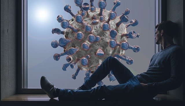 Depressione da Covid-19: un uomo guarda dalla finestra dove campeggia un immagine del virus che ha scatenato la pandemia