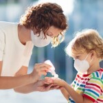 Polmonite, una mamma mette del disinfettante sulle mani di un bambino