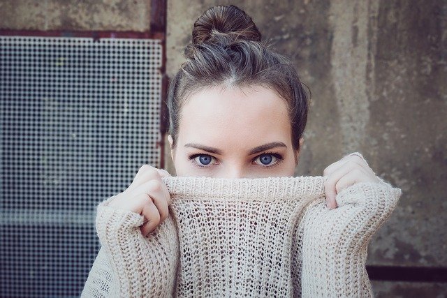 Una donna nasconde il volto dietro il maglione