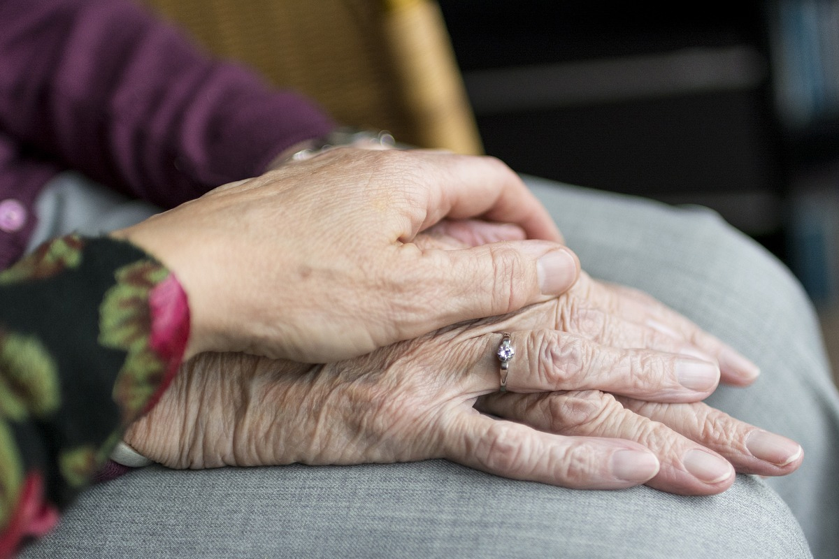 paziente cronico, una mano caregiver su un'altra mano di un'anziana