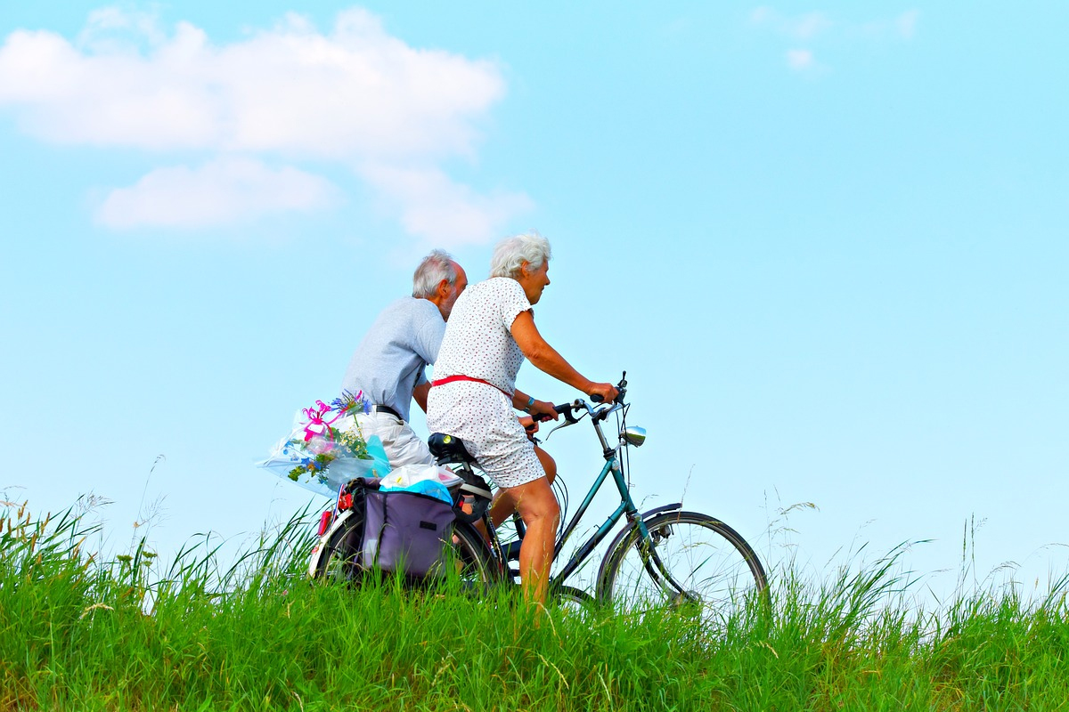 Due anziani in bicicletta in una zona verde della città