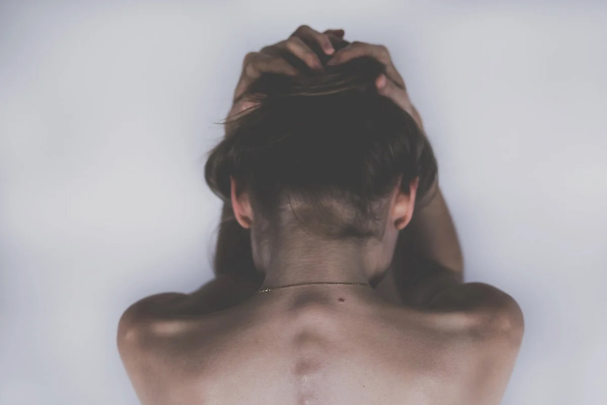 depressione: una donna di spalle si stringe la testa