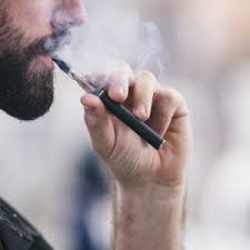 Disfunzione erettile e sigarette elettroniche: in primo piano la bocca e la mano di un uomo di profilo mentre fuma una e-cig e una nuvola di fumo esce dalla bocca