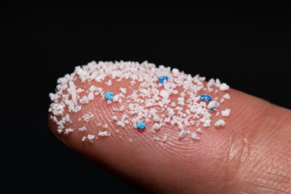 Micro plastic.Small Plastic pellets on the finger.