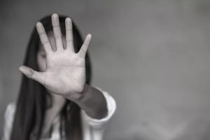 Violenza, una donna in bianco e nero con il palmo della mano aperta in primo piano in segno di stop