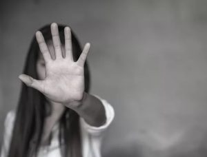 Violenza, una donna in bianco e nero con il palmo della mano aperta in primo piano in segno di stop