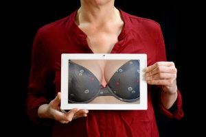 Carcinoma mammario, una donna tiene in mano una foto nella quale si vede un seno fasciato nel reggiseno. Il senso della foto è di parlare di prevenzione del tumore alla mammella