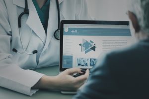 Digital health, un medico mostra schermo al paziente anziano