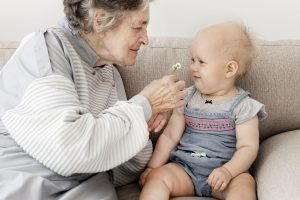 virus respiratorio sicinziale (Rsv): donna anziana e un neonato sul divano sorridono giocando