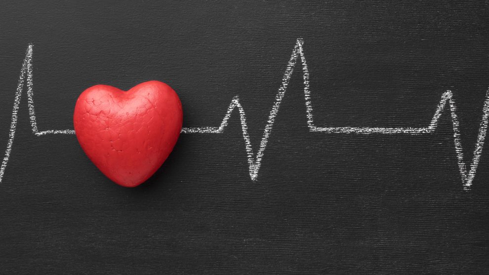 cuore rosso sullo sfondo di una lavagna con disegno di elettrocardiogramma per dare idea dello scompenso cardiaco