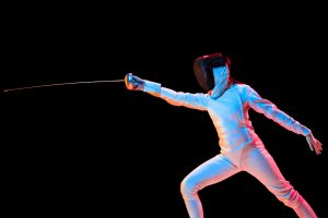 Teen girl in fencing costume with sword in hand isolated on black background Diabete