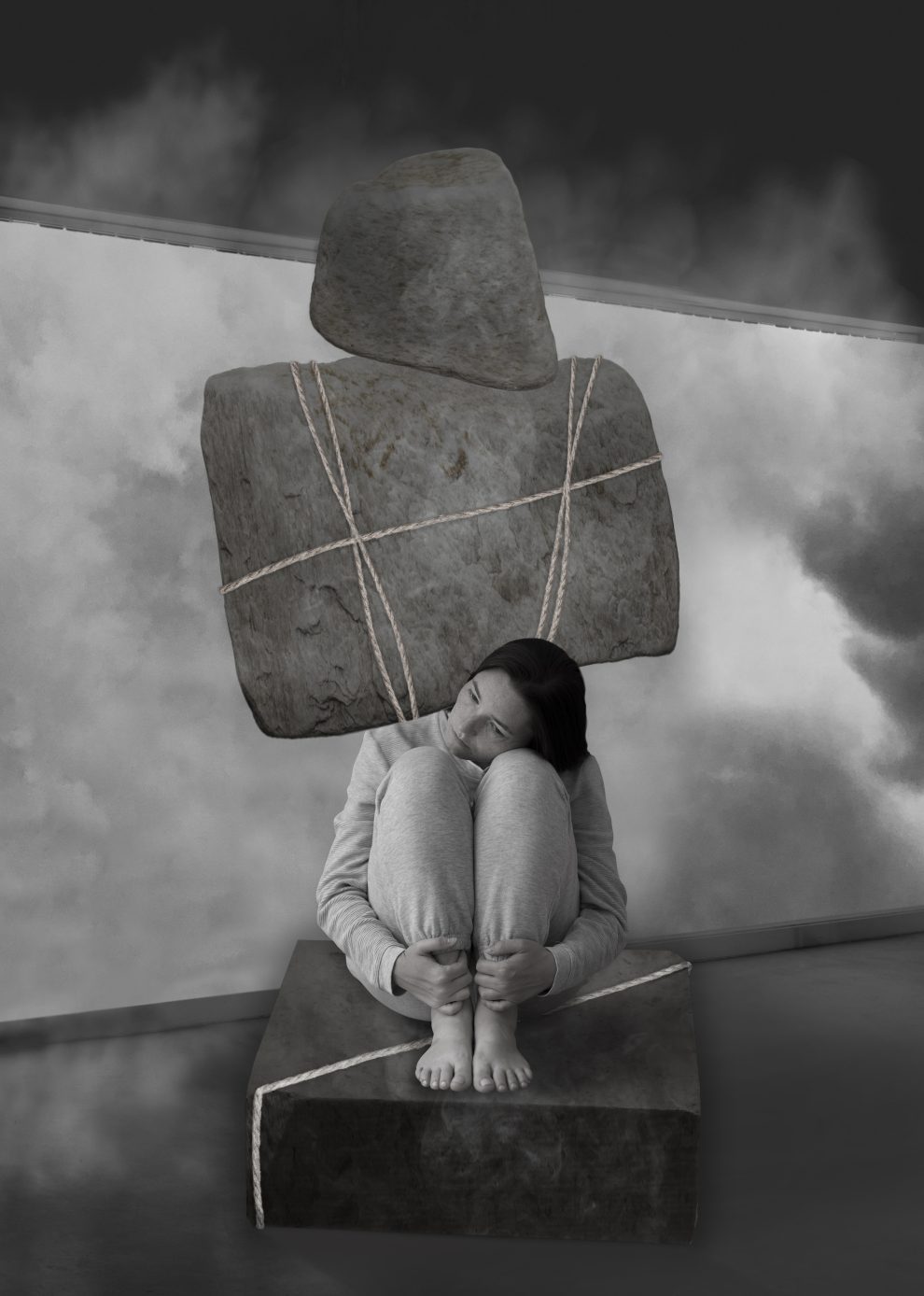depressione, immagine in bianco e nero di una donna accovacciata, sopra la sua testa pende un grande masso