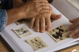 Alzheimer, le mani di due anziani mentre sfogliano un album di foto in bianco e nero