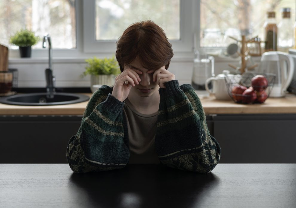 Disturbi alimentari, una ragazza sola in cucina si strofina gli occhi